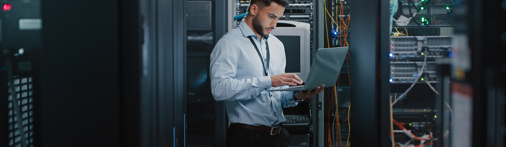 IT manager in server room using a laptop.